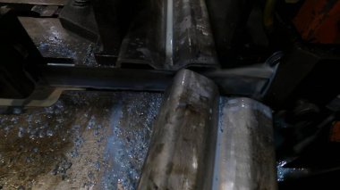 Atölyedeki usta metal için testereyle çalışıyor, makine bıçağı soğutmak için sabunlu su kullanarak çelik profili herhangi bir açıdan kesiyor.