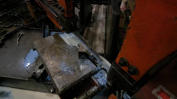 车间的主人用金属带锯工作 机器用肥皂水从任何角度切割钢型材来冷却刀片 — 图库照片