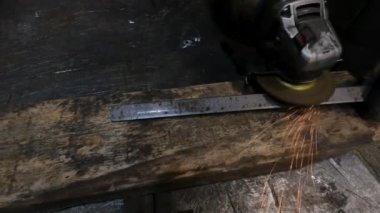 Atölyedeki usta kaynak yapmadan önce paslı bir metal çubuğu öğütücüyle öğütüyor.