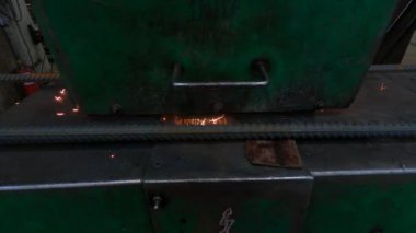 Atölyedeki usta bir kaynak makinesiyle çalışıyor. Metal tüplerin iki parçasını büyük bir güçle ve yüksek sıcaklıkta ısıtıyor. Parçaları birbirine tutturuyor.