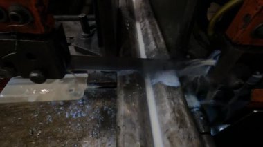 Atölyedeki usta metal için testereyle çalışıyor, makine bıçağı soğutmak için sabunlu su kullanarak çelik profili herhangi bir açıdan kesiyor.