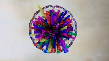 Kokteyller ve diğer içecekler için tüm plastik renkli pipetler bir bardaki ahşap masada yatıyor.