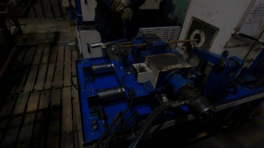 Metal atölyesi ustabaşı çelik parçaları üretiminde iplikler yaratmak için güç makinesiyle çalışıyor.