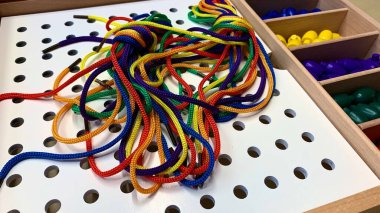 Renkli bağcıklar ve bağcıklar ile ince motor becerileri geliştirmek için çocuk oyunu