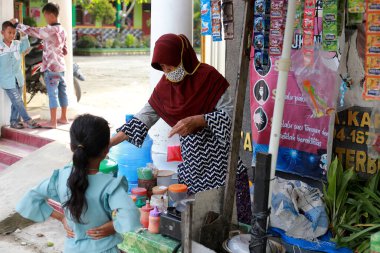 Lampung, Endonezya, 17 Aralık 2021 okul bahçesinde abur cubur satan bir anneye odaklanmış.