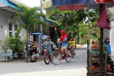 Lampung, Endonezya, 17 Aralık 2021 öğleden sonra arkadaşlarıyla sohbet ederken iki Endonezyalı çocuğun bisiklet sürmesine odaklanmış.