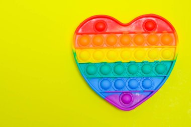 Pop It çocuk oyuncağı, anti-stres, oyuncak, moda oyuncağı, reklam amaçlı, sarı kağıt arka planda izole edilmiş, viral oyuncaklar, renkli, şişmiş,
