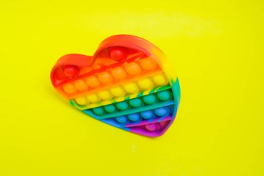 Pop It çocuk oyuncağı, anti-stres, oyuncak, moda oyuncağı, reklam amaçlı, sarı kağıt arka planda izole edilmiş, viral oyuncaklar, renkli, şişmiş,