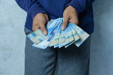 Asyalı adam Rupiah banknotlarını sayıyor ve gösteriyor