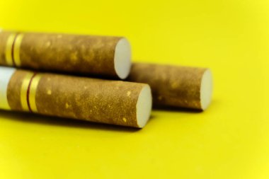 Sarı arka planda izole edilmiş kretek filtreli sigara seti, hastalıklar ve kanser, bağımlılık yapan nikotin