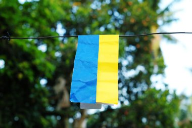 Ukrayna bayrağı konsepti. Kağıt bulanık bir arka planda Ukrayna ulusal renkleriyle boyanmış bir ipe asılı. Ukrayna bayrağı
