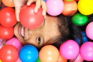 Renkli top sahasında gülümseyen küçük kız.