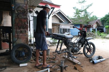 Lampung, Endonezya, 22 Nisan 2022: Bir adam yerel bir motosiklet tamirhanesinde tamirci olarak çalışıyor