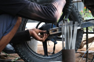 Bir adam yerel bir motosiklet tamirhanesinde tamirci olarak çalışıyor.