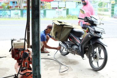 Lampung, Endonezya, 26 Nisan 2022 motosiklet tamircisinin motosiklet lastiklerini şişirmesi