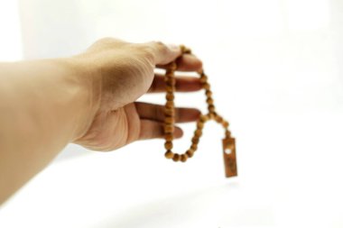 Beyaz arka planda Müslüman boncukları ya da Tasbih 'in elini tutmak. Boşluğu kopyala ve seçici odak