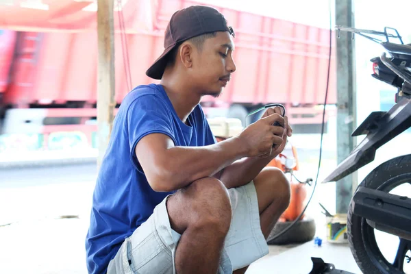 2022年4月26日 印度尼西亚兰榜 一名亚洲男子在摩托车修理店修理手中受损的摩托车电缆 — 图库照片