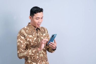 Asyalı adam ifadesi elinde akıllı telefon, batik gömlek giyiyor.