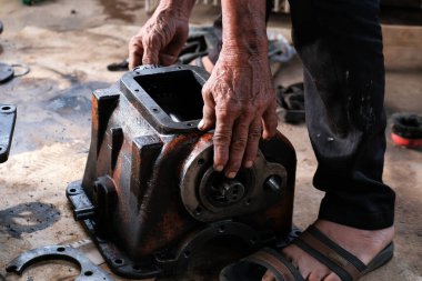 Asyalı adam atölyede çalışıyor, araç-makine aletlerini tamir ediyor.