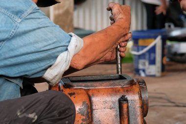 Asyalı adam atölyede çalışıyor, araç-makine aletlerini tamir ediyor.