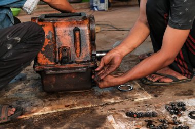 Asyalı adam atölyede çalışıyor, araç-makine aletlerini tamir ediyor.