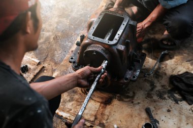 Asyalı adam atölyede çalışıyor, araç-makine aletlerini tamir ediyor.