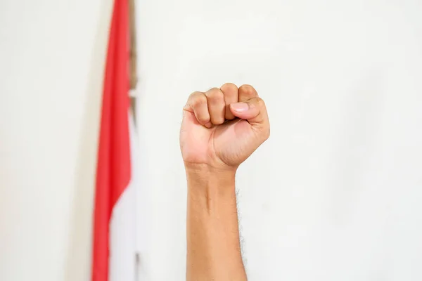  Indonesian youth's hands holding up to celebrate Indonesia's independence day. Cheerful expression over the national flag background