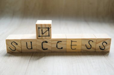 Wooden cube with the text SUCCESS, The word is written on a wooden cube standing on a textured surface.