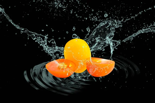 Cherry tomato fruit with water splash isolated on black background with clipping path