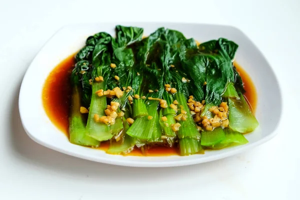 Chinese dish serving on white plate, Bok choy or baby chinese cabbage with oyster sauce and garlic on white background