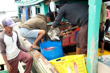 Lampung, Endonezya, 07 Ekim 2022: Endonezyalı erkekler Lampung, Endonezya 'da bir balıkçı teknesinde balık sepetini ayırıyorlar..
