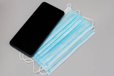 Gri arkaplanda mavi maskeler ve telefon