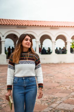 Beyaz bir kadın yürürken gülümsüyor ve elinde bir defter tutuyor. Dikey. Kopyalama alanı ile.