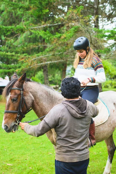 認識できないラテン系の男性は 白人女性に馬に乗る方法を教えています コピースペース付き — ストック写真