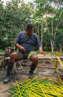 Amerikan yerlisi bitkinin lifini elde etmek için yaprakları kesiyor. Bankta otururken. Ormanda. Dikey. Kopyalama alanı ile.