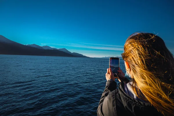 Güneşin doğuşunda dağların fotoğrafını çeken beyaz bir kadının arka planda görüntüsü. Yatay olarak. Kopyalama alanı ile.