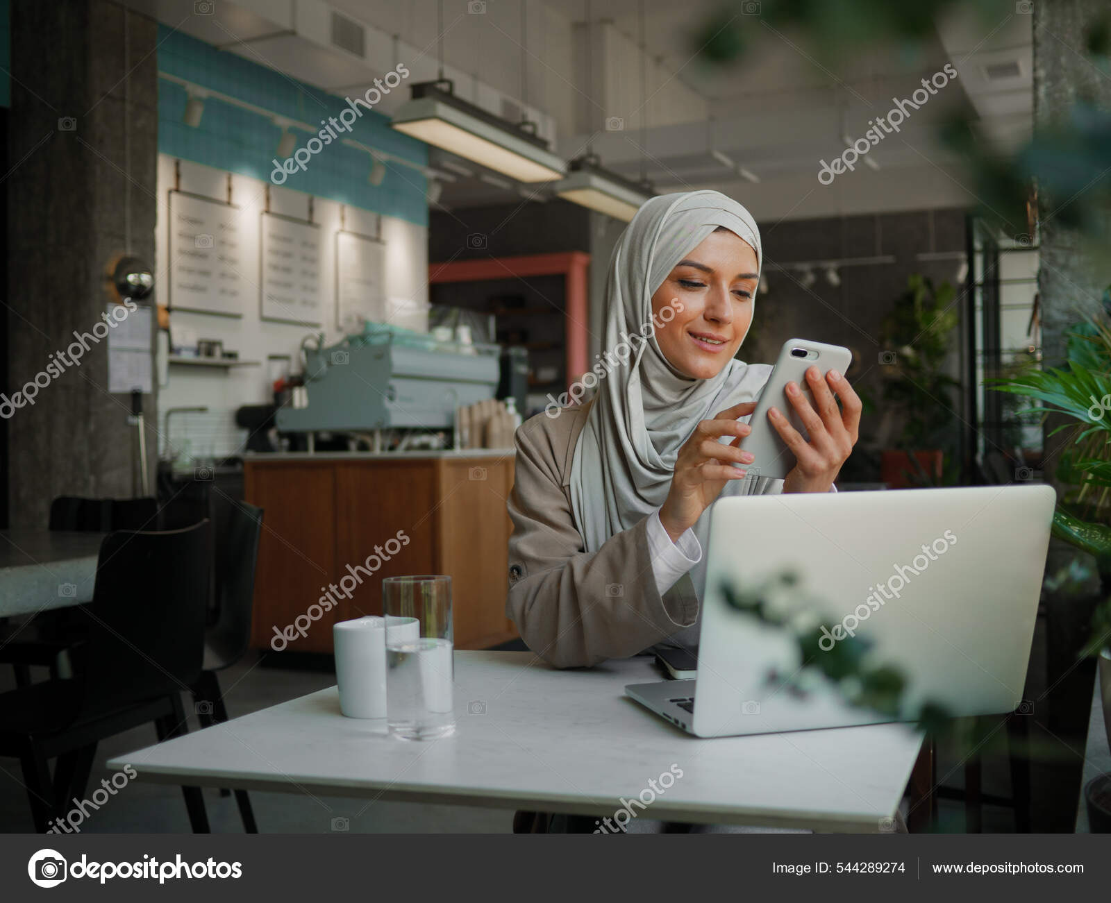 Muslim woman on remote working, online education or video conversation in caffe Stock Photo by