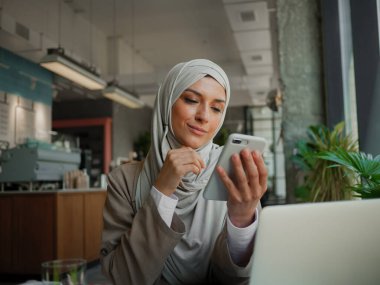 Kafede uzaktan eğitim, çevrimiçi eğitim veya video sohbeti yapan Müslüman kadın
