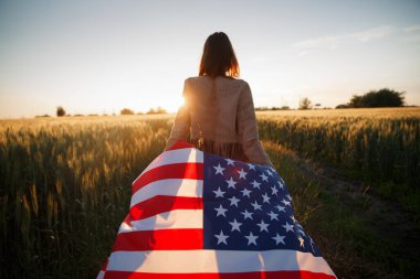 4 Temmuz. 4 Temmuz 'da. Gururlu bir kadın günbatımında Amerika bayrağını güzel bir simgeye taşıyor. Bağımsızlık Günü, Amerikan ulusal vatanseverlik bayramı, demokrasi ve gazi saygı konsepti.