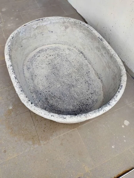 Eski bir havan topu duvarın yanına ve kirli bir zemine konur..