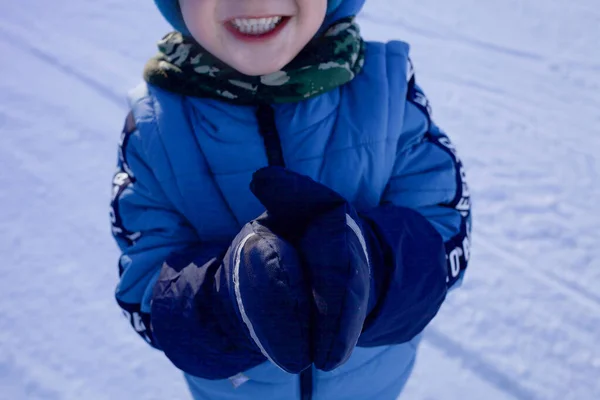 Дитина в рукавичках на тлі засніженої дороги, посміхаючись . — стокове фото