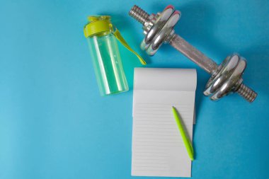 spor dambılı, mavi arka planda bir kalemi olan bir not defteri.