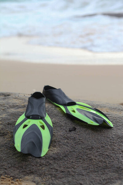 Плавники для подводного плавания лежат на камне у берега океана