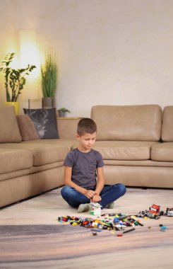 Çocuk halıya oturur ve lego inşaatçısıyla oynar. Yüksek kalite fotoğraf 