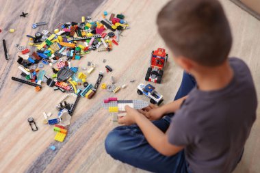 Okul çocuğu yerde bir inşaatçıyla oynuyor.