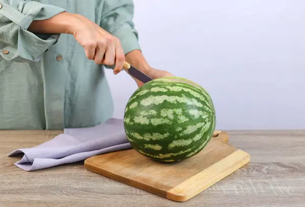 Womans hands cut a watermelon on a board. High quality photo