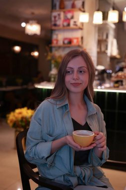 a girl sits in a cafe and holds a cup in her hands. High quality photo