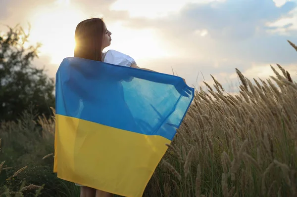 a young girl stands facing the sun with a flag Ukraine