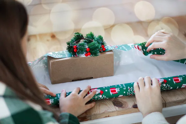 hands of a child and mom wrap a gift for the holiday. High quality photo