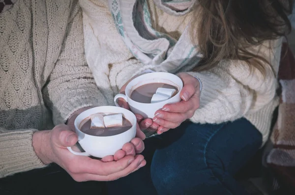 man and woman sitting and holding cocoa with mashmellow. High quality photo